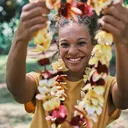 Smiling woman holding up a flower lei