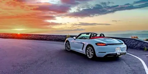 Porsche Boxster convertible on the coast road at sunset