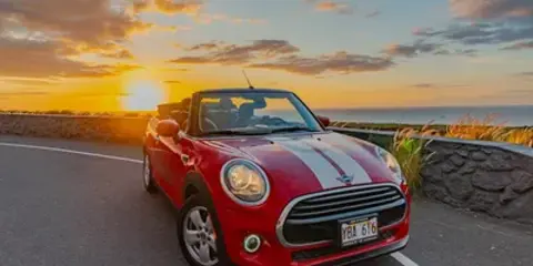 Red Mini Cooper convertible at sunset in Kona