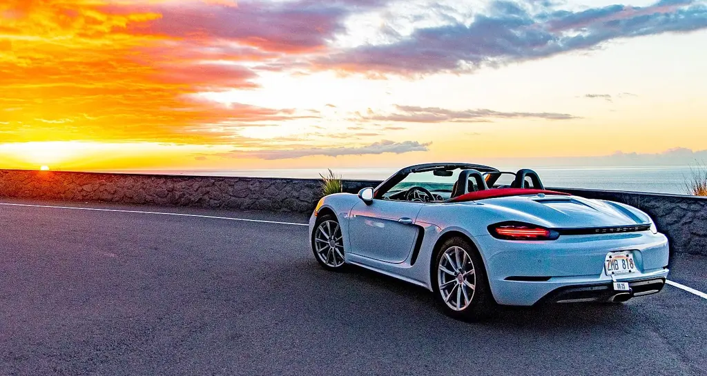 Porsche Boxster convertible rental on scenic Hawaii Big Island road at sunset